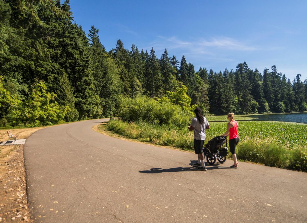 Two people walk with a stroller around the Seward Park northern waterfront loop. 