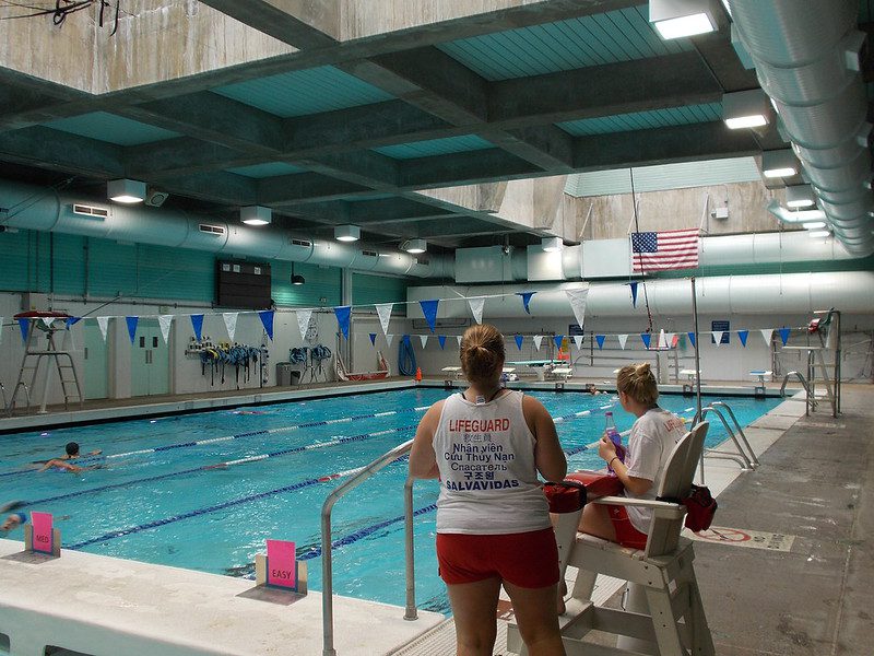 two lifeguards watch over a few swimmers in an indoor pool