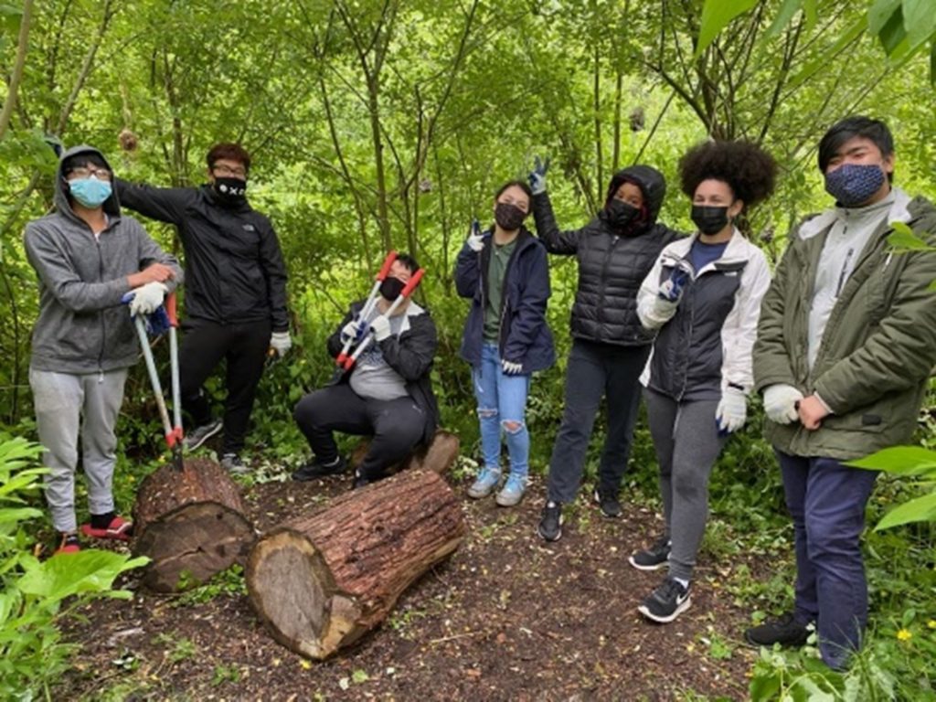 Seven youth gather round for a photo while volunteering in one of Seattle's greenspaces. 