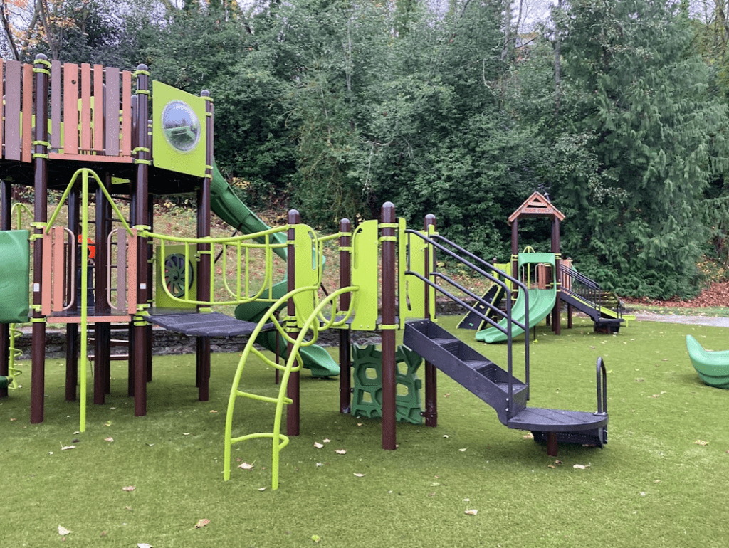 green and brown play structures with climbing opportunities and slides