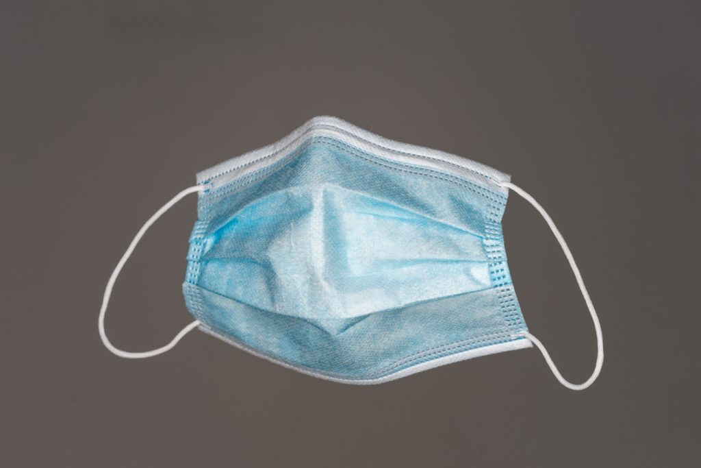 Photo of a blue cloth face mask with elastic ear bands, typically used for medical or COVID-19 protection.