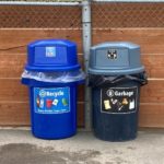 A blue trash can labeled "Recycle" next to a black trash can labeled "Garbage"