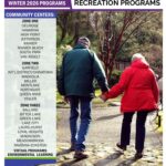 An older couple holds hands while walking on a stone path.